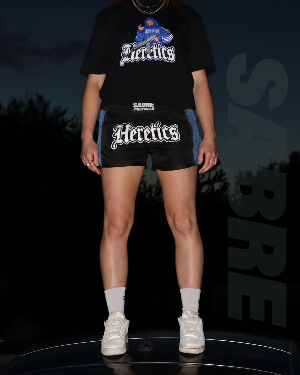 Female fighter wearing the limited-edition HERETICS women's Muay Thai shorts by Sabre Fightwear x Her Fight Network.
