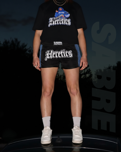 Female fighter wearing the limited-edition HERETICS women's Muay Thai shorts by Sabre Fightwear x Her Fight Network.